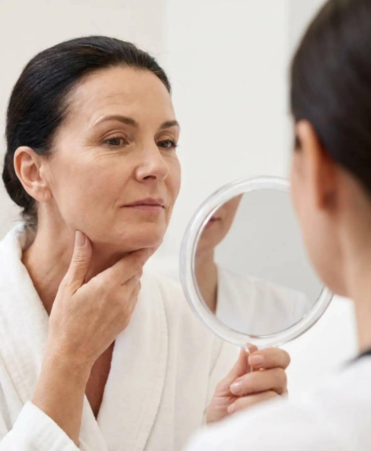 Woman examining fine lines and loose skin before Plasma IQ skin tightening treatment