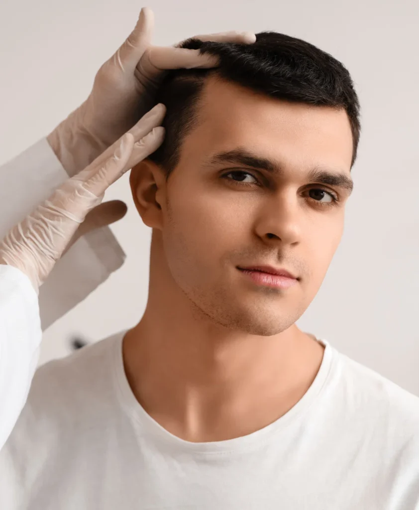 Gloved hands examining a man’s hairline